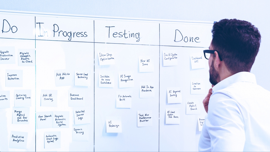 Homem analisando tarefas em quadro Scrum