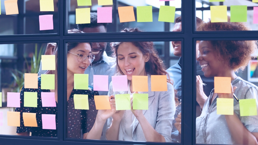 Mulheres discutindo conteúdo em frente a parede com post its